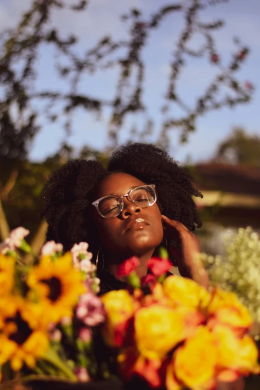 a woman standing in front of a bunch of flowers, an album cover, pexels contest winner, amber glasses, natural hair, sun down, kezie demessance