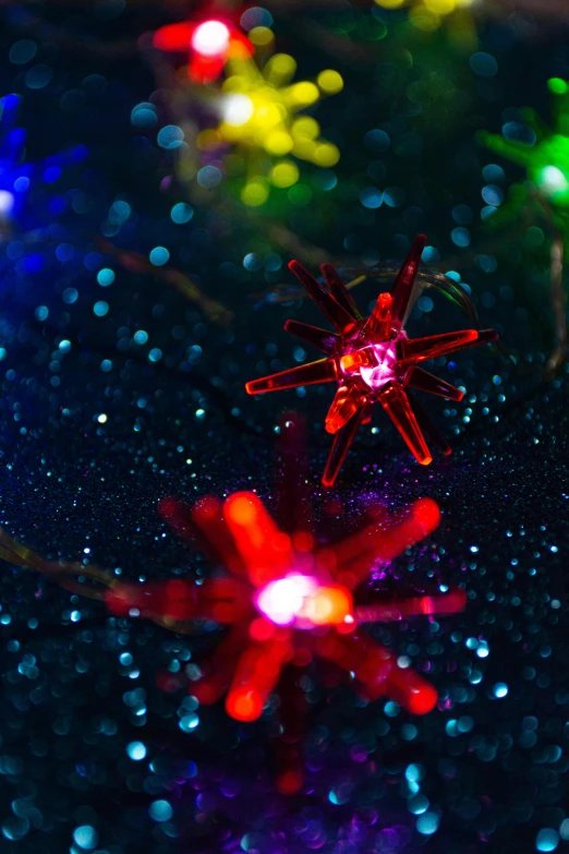 a bunch of lights that are on a table, a microscopic photo, inspired by Bruce Munro, pexels, light and space, light red and deep blue mood, colorful stars, detail shot, ornament