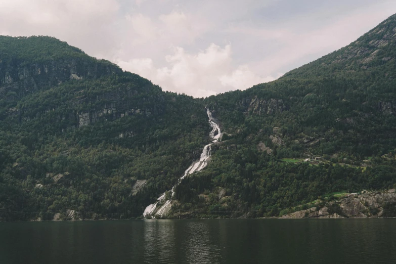 a body of water with a mountain in the background, waterfall falling down, fjord, the photo was taken from afar, thumbnail