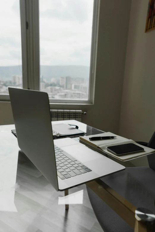 a laptop computer sitting on top of a desk next to a window, pexels, on a cloudy day, ceo, angle view, multiple stories