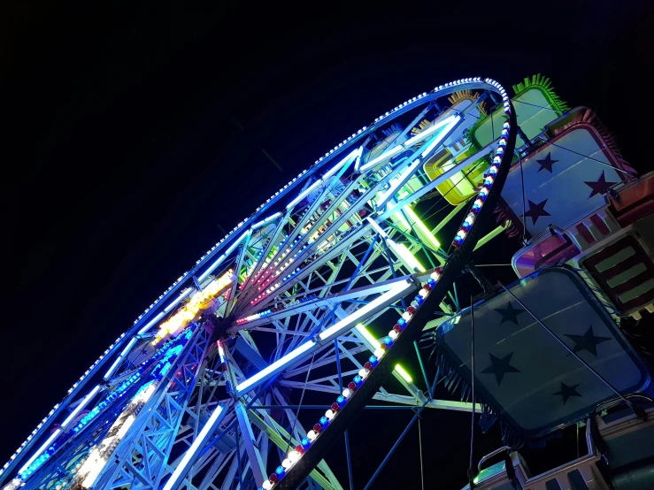 a ferris wheel is lit up at night, pexels contest winner, avatar image, low angle photo, blue neon, gopro photo
