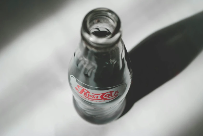 a coke bottle sitting on top of a table, pexels contest winner, photorealism, grey, small, morning sunlight, round bottle