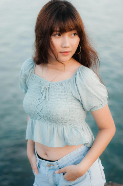 a woman standing next to a body of water, an album cover, trending on pexels, renaissance, young cute wan asian face, croptop, light-blue, puff sleeves