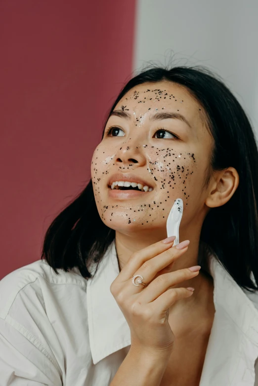 a woman brushes her face with a brush, by Julia Pishtar, happening, white with black spots, silicone skin, gemma chen, she is happy