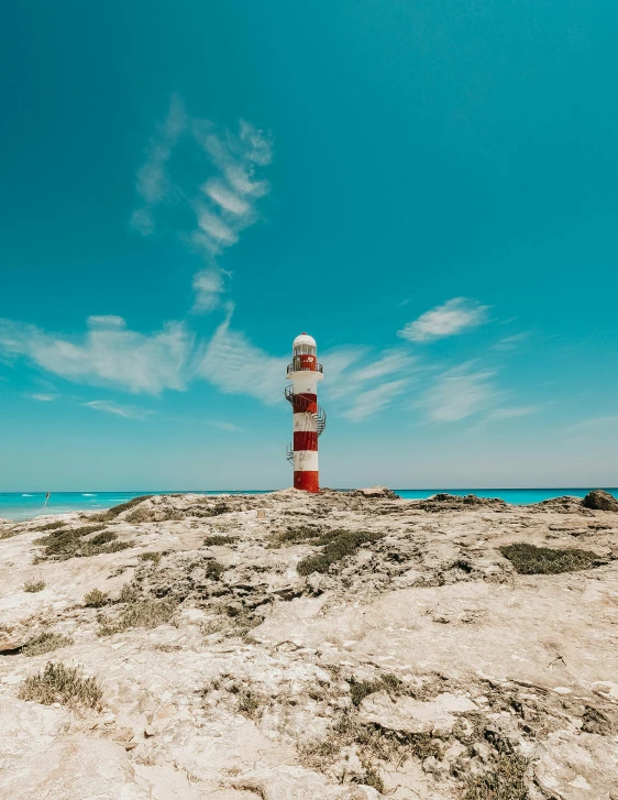 a red and white lighthouse sitting on top of a sandy beach, pexels contest winner, mexico, 🚿🗝📝, profile image, rocky seashore