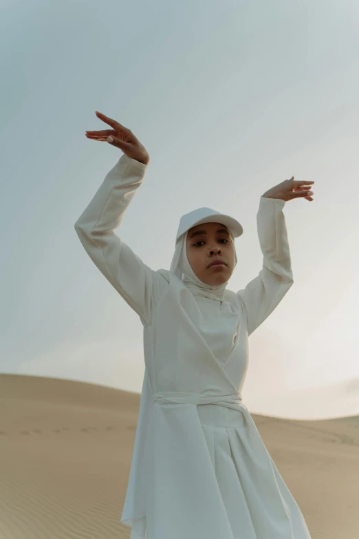 a woman in a white dress in the desert, an album cover, inspired by Li Di, unsplash, afrofuturism, wearing a tracksuit, muslim, battle pose, ( ( theatrical ) )