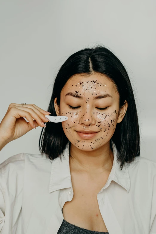 a woman brushing her teeth with a toothbrush, a black and white photo, by Julia Pishtar, trending on pexels, happening, made of dots, mud on face, asian face, black eye mask