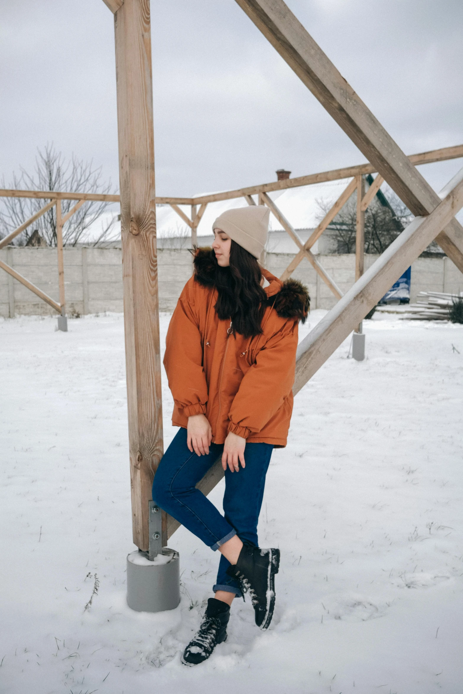 a woman sitting on a pole in the snow, a picture, trending on pexels, orange jacket, casual streetwear, brown, fullbody photo