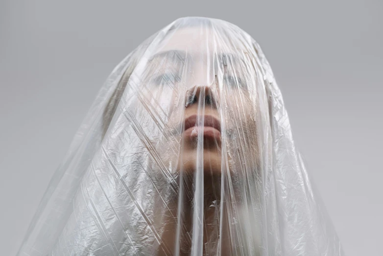 a woman with a veil covering her face, an album cover, inspired by Elsa Bleda, pexels contest winner, hyperrealism, dressed in plastic bags, anna nikonova aka newmilky, ignant, nun fashion model looking up