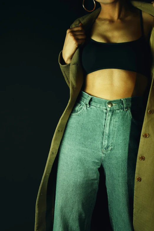 a woman standing in front of a black background, an album cover, inspired by Elsa Bleda, trending on pexels, worn pants, dirty green clothes, wearing a crop top, 1996)