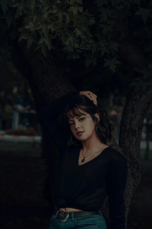 a woman leaning against a tree in a park, inspired by Elsa Bleda, unsplash contest winner, realism, with a dark fringe, wearing a black shirt, concert, dark ominous mood