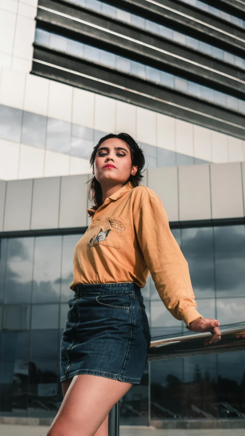 a woman standing in front of a tall building, an album cover, inspired by Elsa Bleda, pexels contest winner, renaissance, wearing polo shirt, ocher, 15081959 21121991 01012000 4k, long sleeves