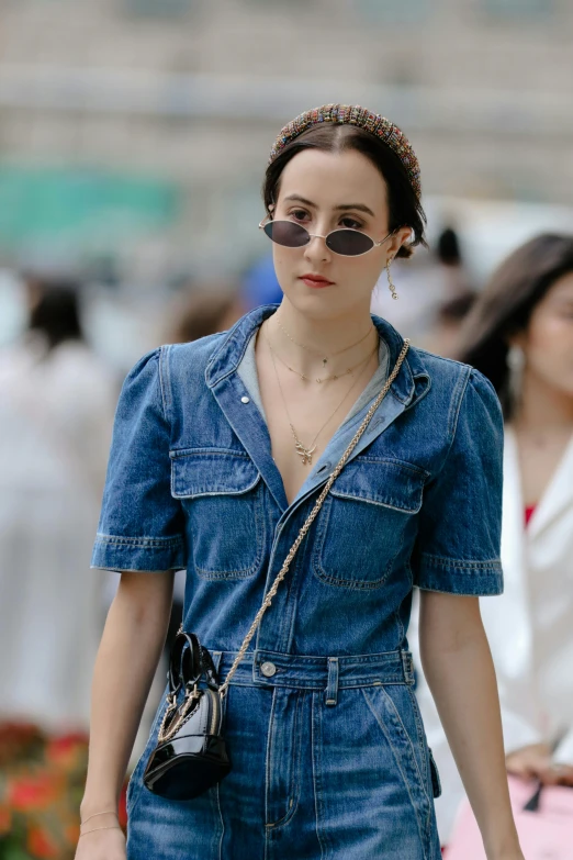 a woman in a denim jumpsuit walking down the street, inspired by Anita Malfatti, trending on pexels, renaissance, wear ray - ban glass, dilraba dilmurat, wearing several pendants, fan bingbing