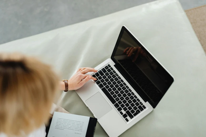 a woman sitting on a bed using a laptop computer, pexels contest winner, high angle close up shot, sat in an office, thumbnail, slightly minimal