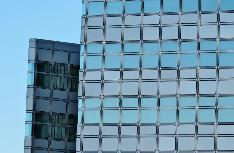 a couple of buildings that are next to each other, inspired by Bauhaus, unsplash, modernism, steel window mullions, silver and blue colors, zoomed in, square shapes