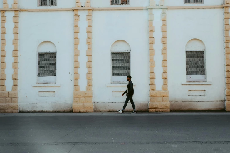 a man walking down the street in front of a building, by Ahmed Yacoubi, pexels contest winner, postminimalism, teenage boy, preserved historical, background image