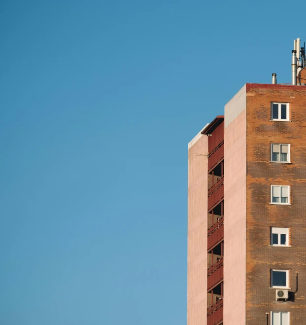 a tall building with a clock on top of it, by Sven Erixson, pexels contest winner, soviet apartment, cloudless blue sky, pink, brown