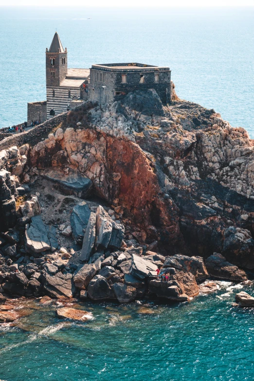 a castle sitting on top of a rock next to the ocean, count of monte cristo, rocky terrain, colour photo, rust