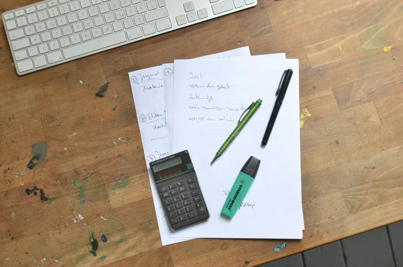 a wooden table topped with papers and a calculator, a sketch, arbeitsrat für kunst, mobile learning app prototype, writing a letter, thumbnail, product introduction photo
