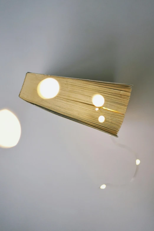 a close up of a light on a wall, by Shigeru Aoki, conceptual art, books flying around, light wood, overhead lighting, 2010s