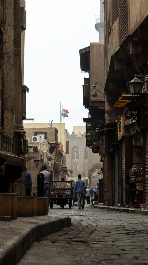 a group of people walking down a street next to tall buildings, an album cover, by Ahmed Yacoubi, pexels, renaissance, cairo, old buildings, assyrian, low fi