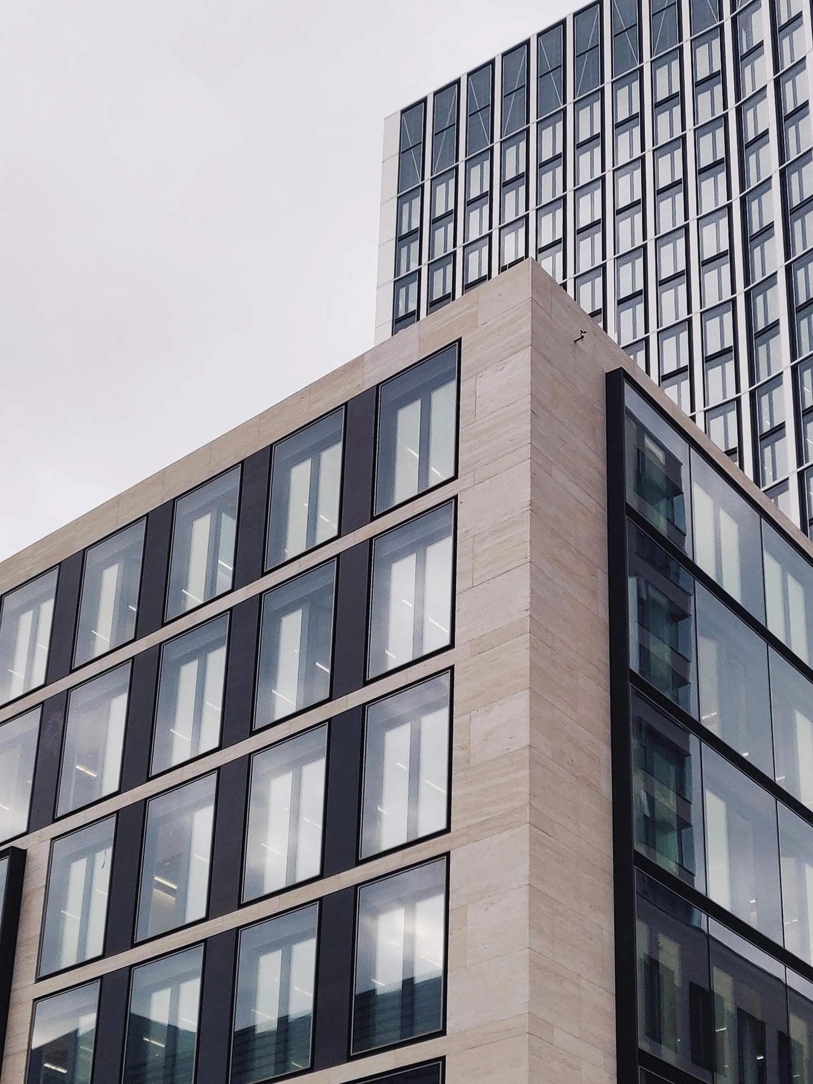 a couple of tall buildings sitting next to each other, inspired by David Chipperfield, unsplash, low quality photo, thumbnail, iron cladding, stone and glass