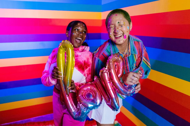 a couple of people standing next to each other holding balloons, neon rainbow drip paint, bowater charlie and brom gerald, mix of ethnicities and genders, laughing out loud