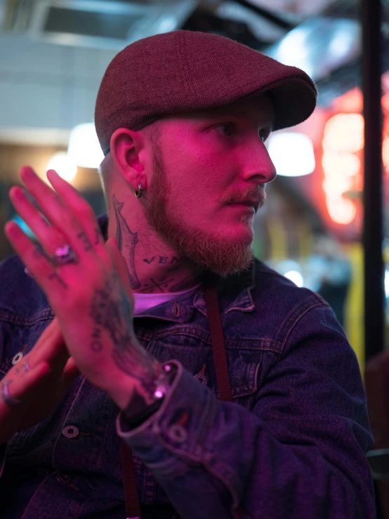 a man sitting at a table with his hands in the air, a tattoo, by David Begbie, pexels, sitting at a bar, bisexual lighting, slightly smirking, hand holding cap brim
