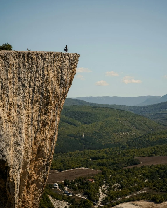 a person standing on top of a cliff, by Daniël Mijtens, les nabis, lourmarin, a gigantic, sitting on top a table, belaying