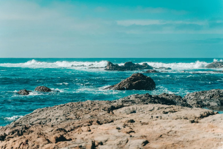 a man standing on top of a rock next to the ocean, pexels contest winner, warm shades of blue, central california, waves crashing at rocks, youtube thumbnail