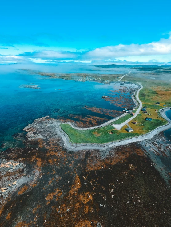 an aerial view of a large body of water, by Roar Kjernstad, pexels contest winner, orkney islands, natural stone road, island in the background, cloudless-crear-sky