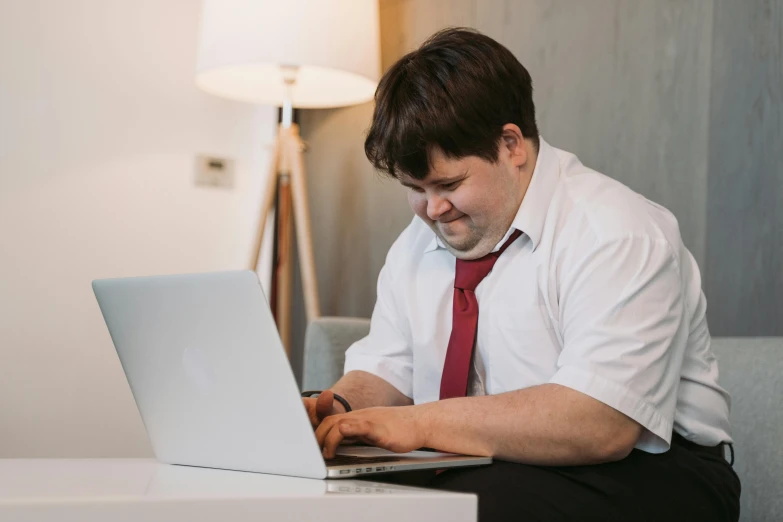 a man sitting on a couch using a laptop computer, unsplash, an obese, lachlan bailey, avatar image, sitting in office