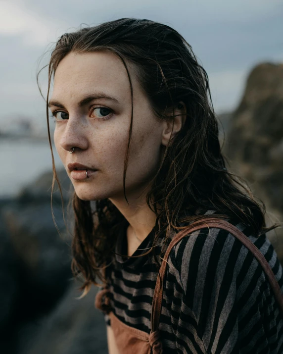 a woman standing on top of a rocky beach, a character portrait, inspired by Elsa Bleda, unsplash contest winner, renaissance, close - up face portrait, wet hair, greta thunberg, near a jetty