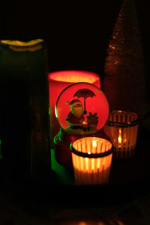 a group of candles sitting on top of a table, by Joe Stefanelli, snowglobe, red and yellow light, a green, low-light photograph