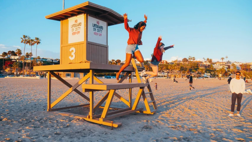 a couple of people standing on top of a lifeguard tower, by Julia Pishtar, unsplash contest winner, happening, jumping for joy, oceanside, sitting on top a table, neighborhood