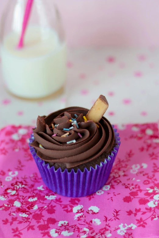 a chocolate cupcake sitting on top of a pink napkin, by Helen Stevenson, full product shot, milkshake, purple, bark