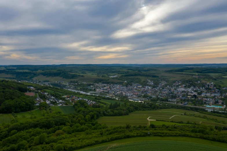 a view of a town from the top of a hill, by Matthias Stom, pexels contest winner, happening, detmold, green valley below, ultrawide landscape, high quality photo