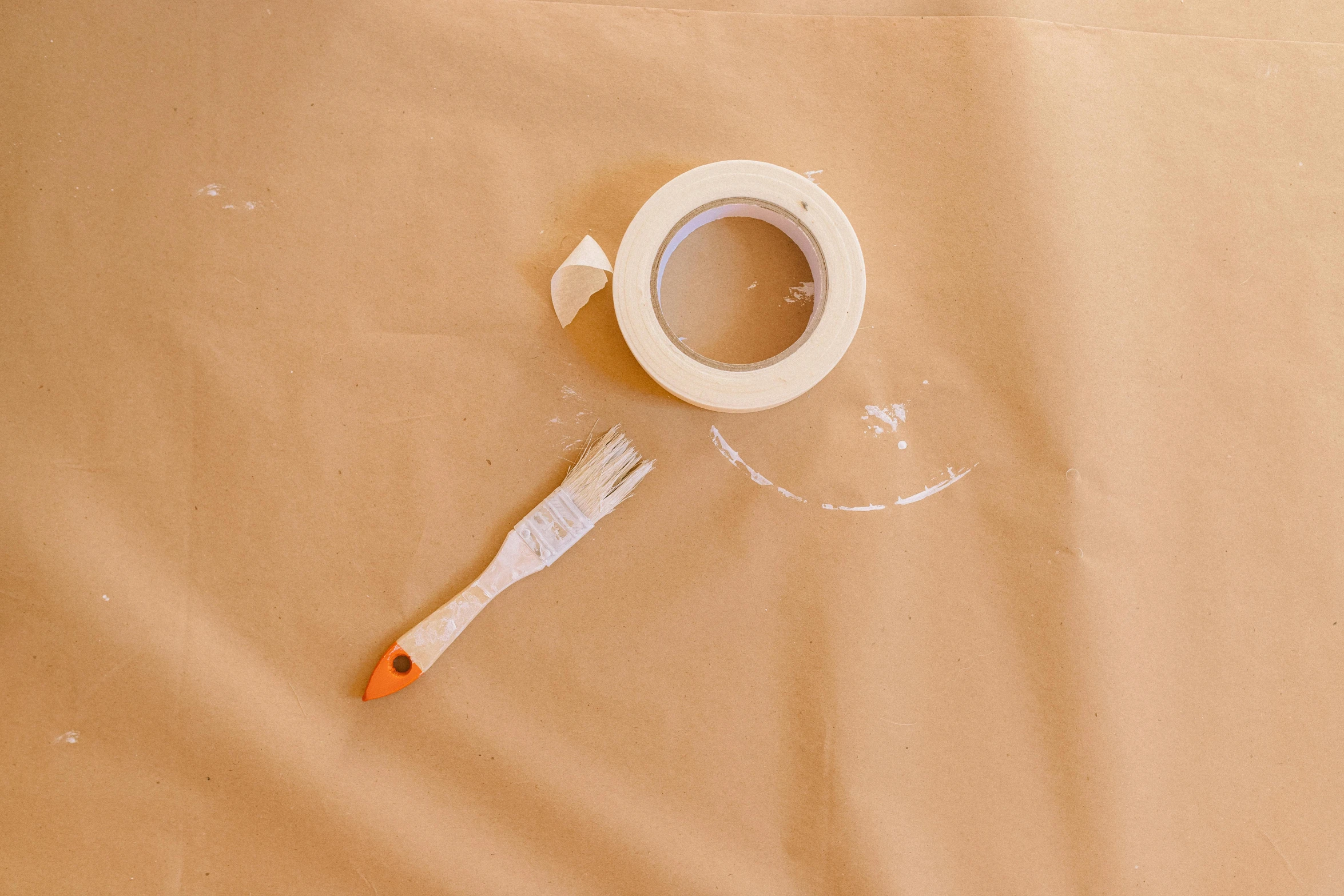 a roll of tape sitting on top of a table next to a toothbrush, inspired by Brett Whiteley, pexels contest winner, action painting, brown paper, white sweeping arches, white paint, spoon placed