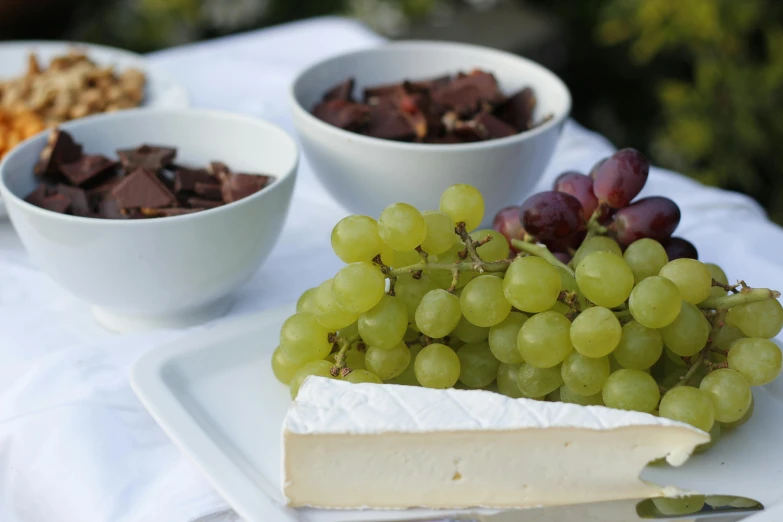 a white plate topped with cheese and grapes, unsplash, private press, al fresco, background image, digital image