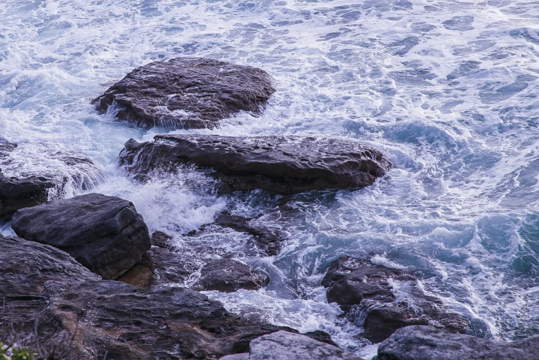 a couple of large rocks sitting on top of a body of water, an album cover, unsplash, australian tonalism, blue crashing waves, ((rocks)), purple water, detailed photo 8 k