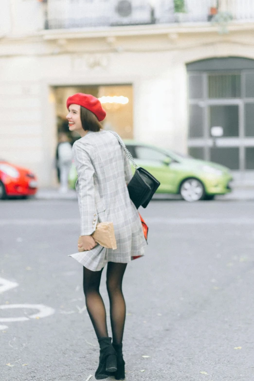 a woman standing in the middle of a street, wearing a french beret, 💋 💄 👠 👗, red and grey only, square