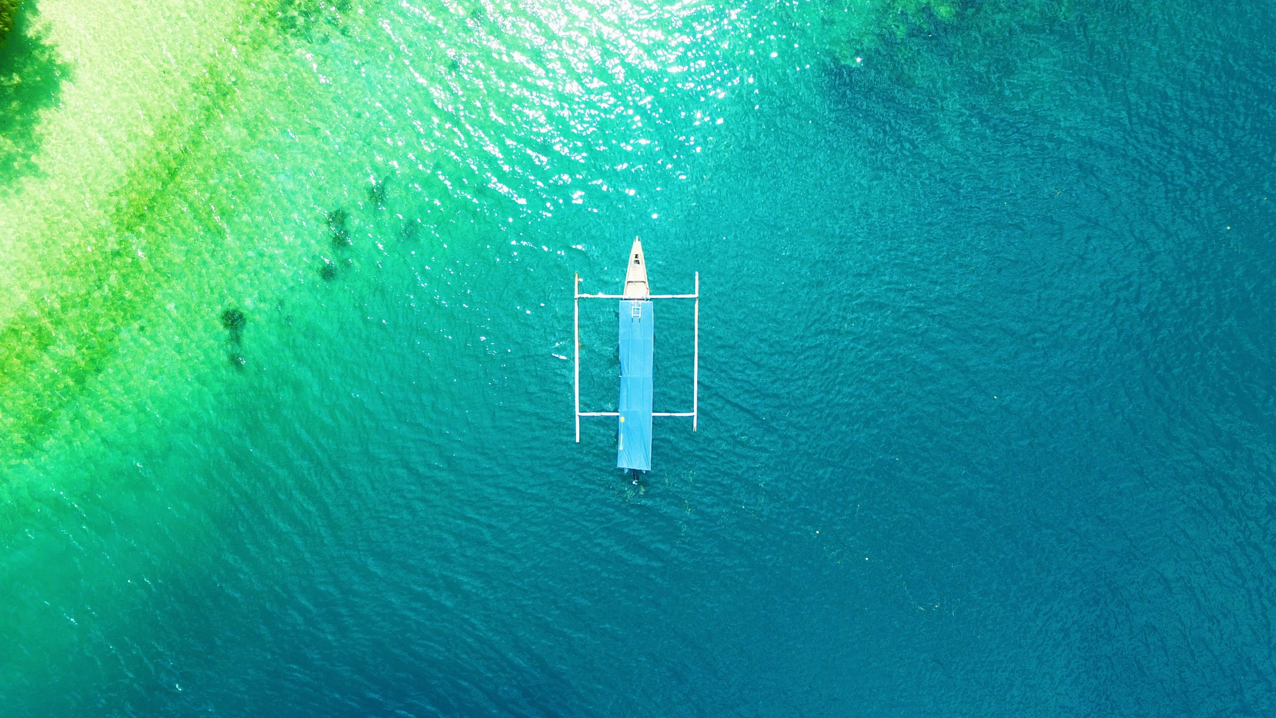 a boat floating on top of a body of water, blue and green water, overhead, philippines, teaser