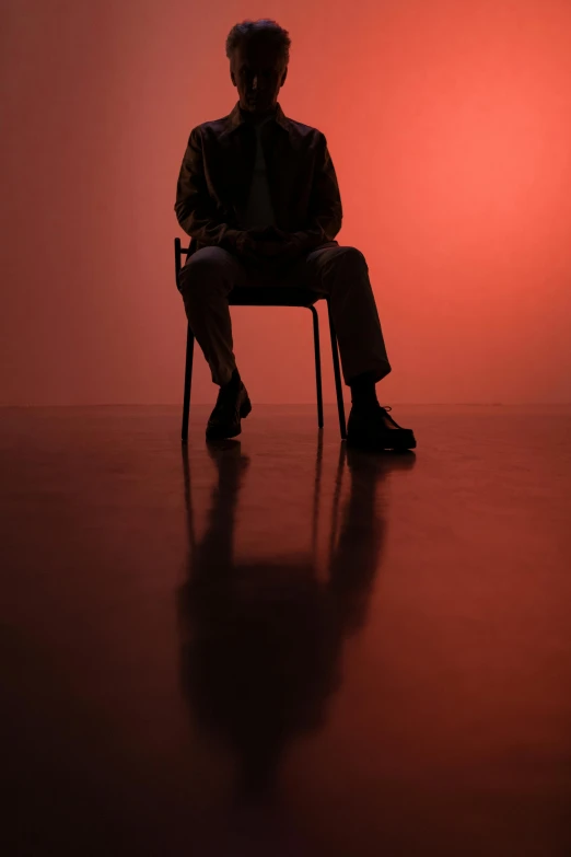 a man sitting on a chair in a dark room, an album cover, pexels, hyperrealism, red haze, soft shadow, black man, 15081959 21121991 01012000 4k