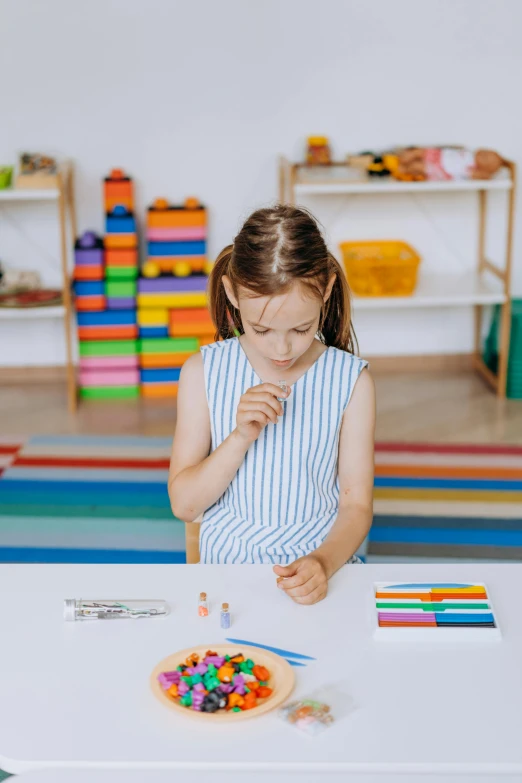 a little girl that is sitting at a table, educational supplies, smoking a joint, striped orange and teal, lego style