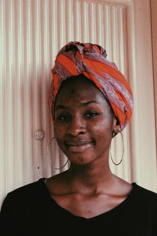 a woman standing in front of a door wearing a turban, by Ella Guru, black scars on her face, post graduate, african facial features, wearing a headband