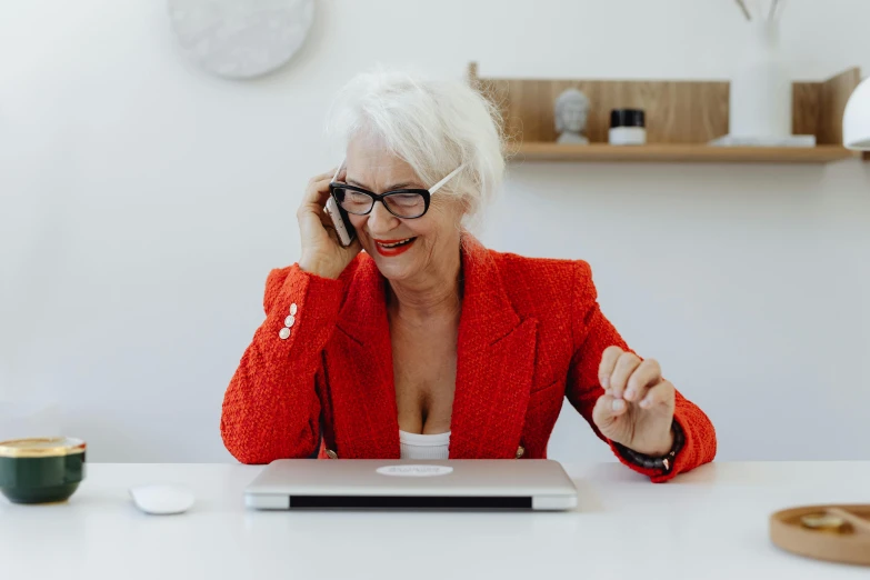 a woman sitting at a table talking on a cell phone, by Lee Loughridge, trending on pexels, an old lady with red skin, typing on laptop, sassy pose, lachlan bailey