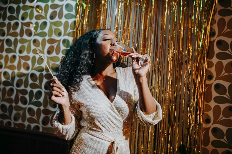 a woman in a white dress drinking a glass of wine, pexels contest winner, happening, wearing disco suit, draped in silky gold, sza, beaded curtains