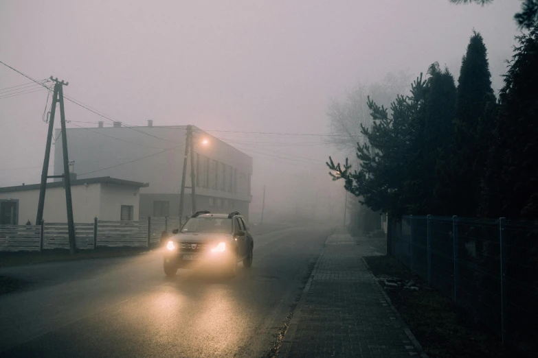 a car is driving down a foggy street, inspired by Elsa Bleda, pexels contest winner, romanticism, overcast dawn, szekely bertalan. atmospheric, magical soviet town, headlights