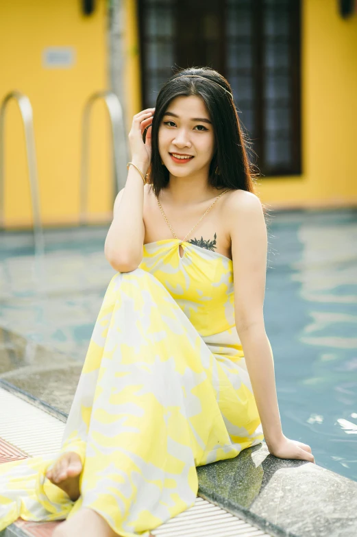 a woman sitting on the edge of a swimming pool, a picture, inspired by Xie Sun, instagram, wearing a yellow dress, relaxing and smiling at camera, in style of lam manh, profile image