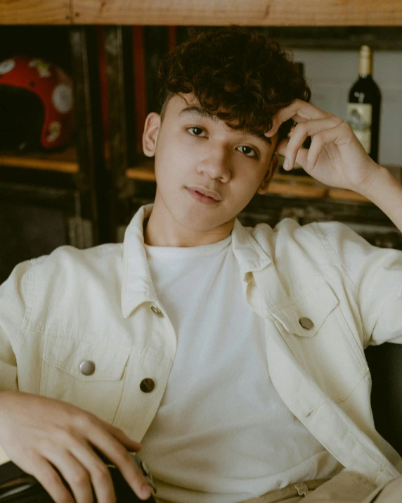 a close up of a person sitting in a chair, an album cover, inspired by John Luke, trending on pexels, sumatraism, masculine pose, androgynous, leaning on door, white sleeves